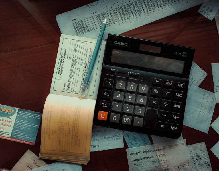 Calculatrice Casio posée sur un bureau au milieu de factures et de reçus manuscrits