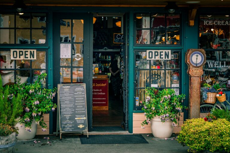 Devanture chaleureuse d'une épicerie et café indépendant, avec pancartes Open et plantes en pot